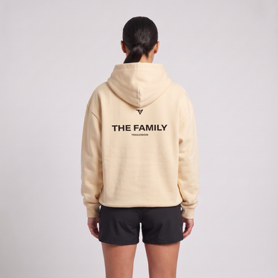 Female model wearing The Family Hoodie in Mild Apricot, rear view with large back print