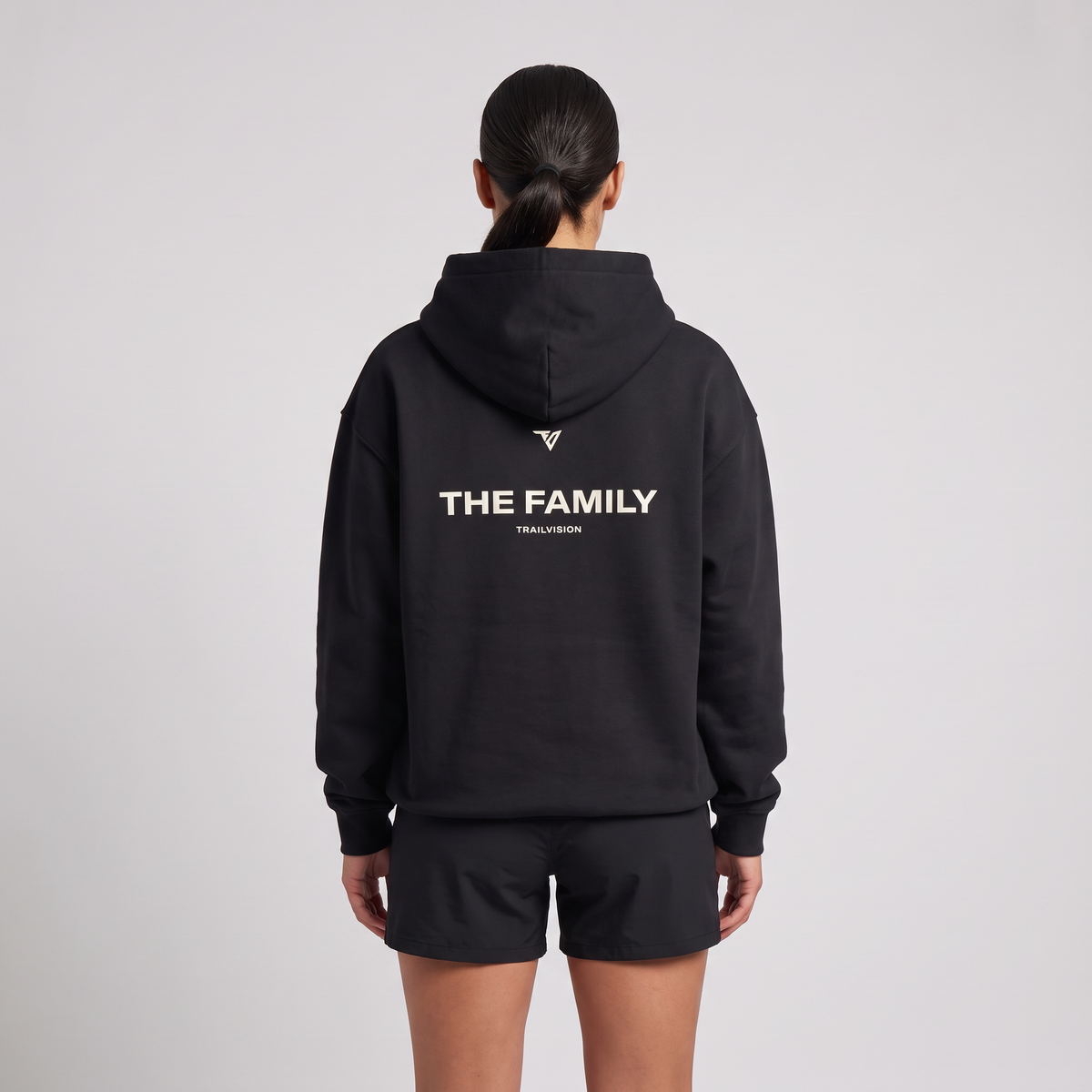 Female model wearing The Family Hoodie in black, rear view with large back print