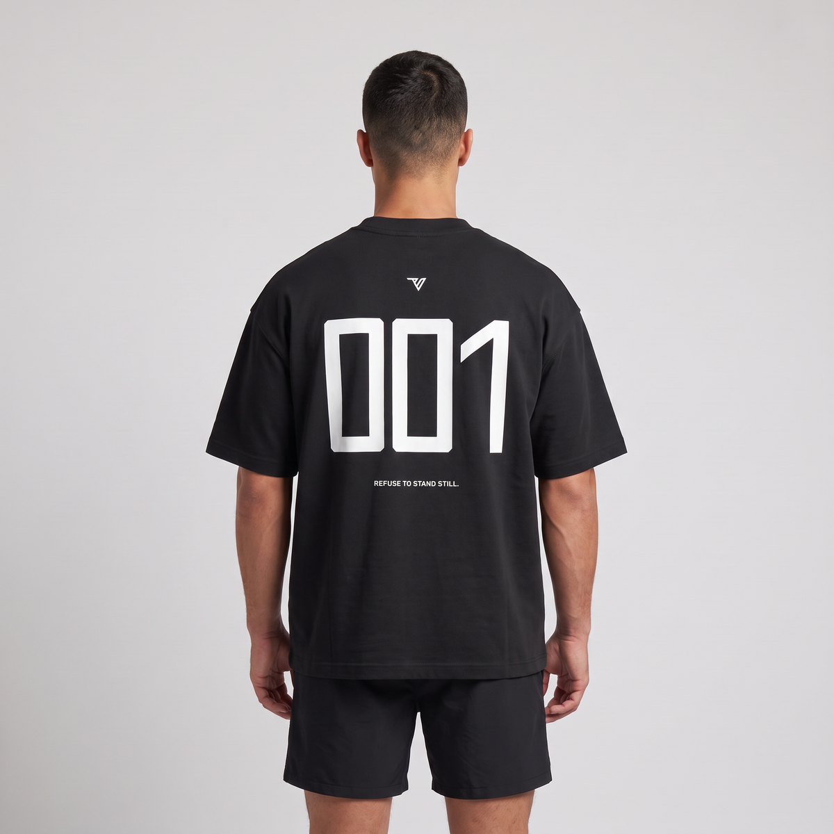 Male model wearing the 001 Oversized Tee in black, rear view with large 001 back print