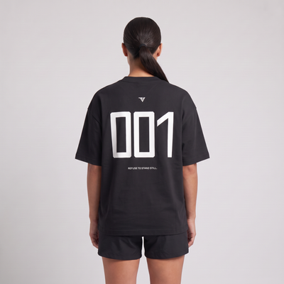 Female model wearing the 001 Oversized Tee in black, rear view with large 001 back print