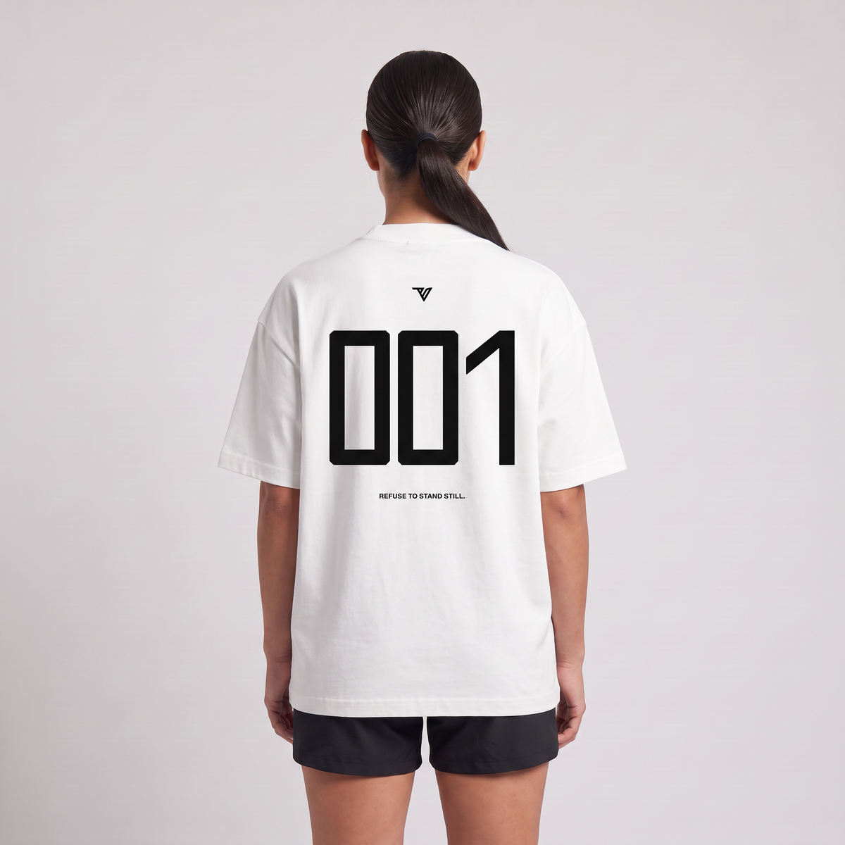 Female model wearing the 001 Oversized Tee in white, rear view with large 001 back print