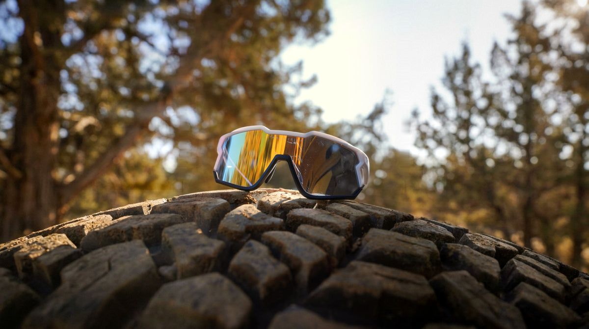 White Trailvision shield sunglasses with gold mirror lens on an off-road tire